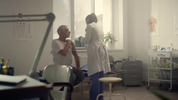 Medical specialist injecting vaccine to senior patient shoulder in hospital. — Αρχείο Βίντεο