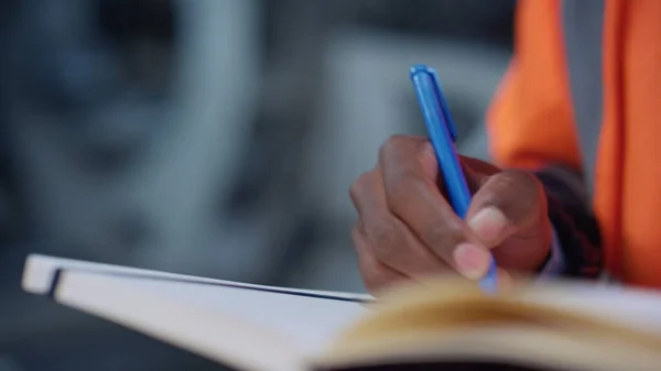 Analyst hands writing notes at factory closeup. Brown skin man use notebook