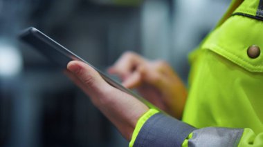 Modern fabrika imalatı üzerine tablet bilgisayarı bantlayan yakın çekim elleri.