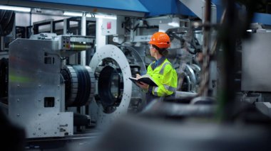 Odaklanmış mühendis büyük üretim tesisinde defter yazıyor..