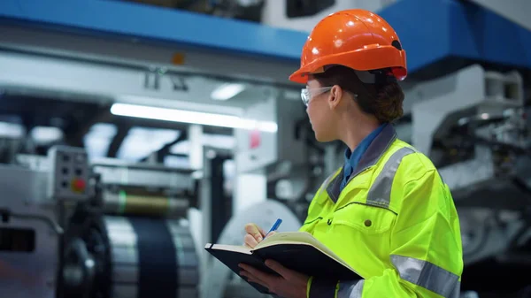 Industrial worker writing project note pad on big manufacture facility closeup