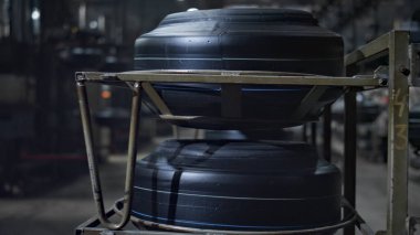 Modern fabrikada yürüyen işçi silueti ile araba lastiği depolama manzarası 