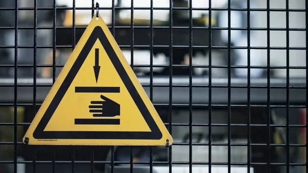 Κίτρινη πινακίδα ασφαλείας εργοστασίου στο δίκτυο στο φόντο μηχανών βιομηχανικών εγκαταστάσεων — Φωτογραφία Αρχείου