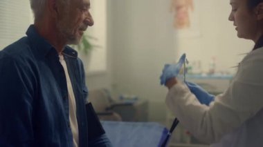 Steteskop kullanan yaşlı bir kadın terapist klinikte nabzını kontrol ediyor..