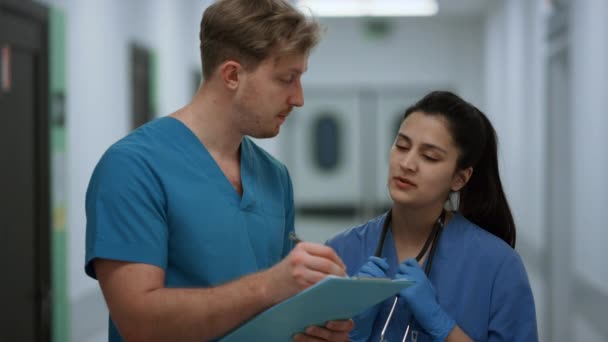 Surgeon discussing patient diagnosis with nurse standing clinic corridor closeup — Vídeo de stock