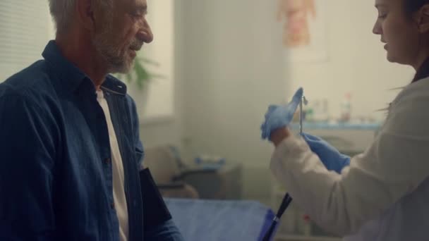 Mujer terapeuta revisando pulso paciente anciano en clínica usando estetoscopio. — Vídeo de stock