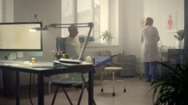 Klinikte aşı bekleyen kıdemli bir hasta var. Kadın doktor aşıyı hazırlıyor..