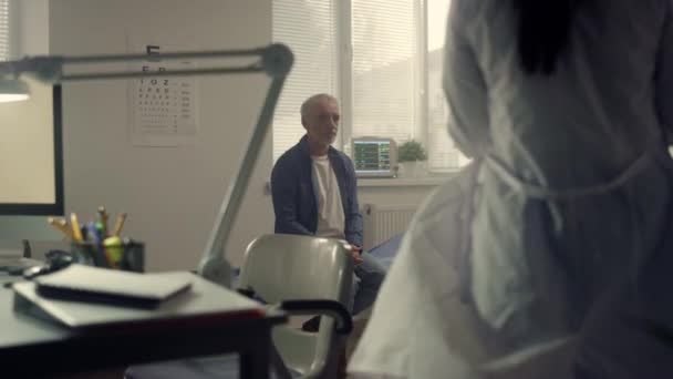 Doctor consulting old man in clinic. Woman physician talking with senior patient — Αρχείο Βίντεο