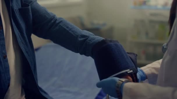 Donna medico mettere bracciale misurazione della pressione sanguigna sul braccio vecchio primo piano. — Video Stock