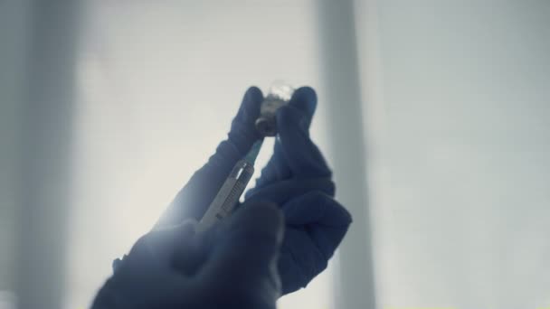 Handen van de arts die de spuit vullen met antivirale medicatie die de injectieflacon dicht houdt. — Stockvideo