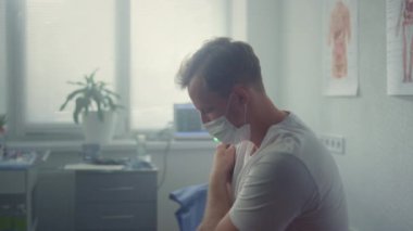 Man patient holding shoulder after vaccination sitting modern clinic close up. 
