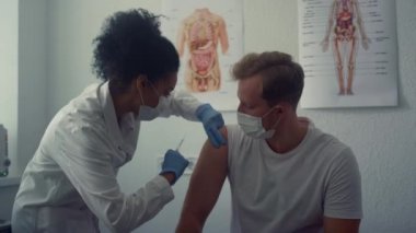 Physician making vaccine injection in man shoulder. Doctor vaccinating patient.