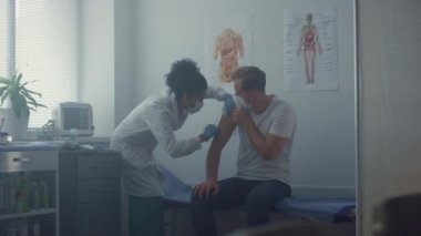Medic making patient vaccine injection in clinic office. Doctor vaccinating man.