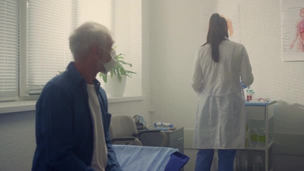 Le vieil homme attend un examen médical à la clinique. Médecin préparant le test. — Video