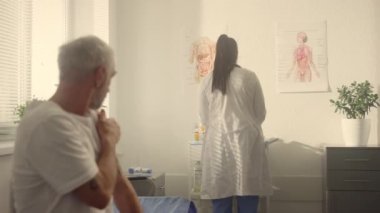 Elderly man holding shoulder after vaccine in clinic closeup. Prevention concept