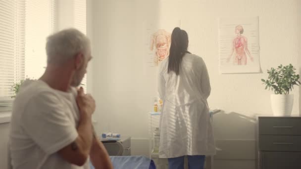 Ηλικιωμένος άντρας που κρατάει τον έναν ώμο μετά τον άλλο σε κοντινό πλάνο κλινικής. Έννοια πρόληψης — Αρχείο Βίντεο