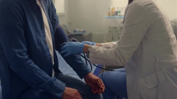 Las manos del médico colocan un brazalete médico en el brazo del paciente de cerca. Presión de medición — Vídeo de stock