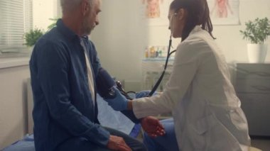 Klinikteki baskı hastalarını kontrol eden terapist kapatıyor. Doktor yaşlı adamı muayene ediyor.