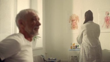 Doktor muayenehanesinde kıdemli bir hasta aşı olmaya hazırlanıyor..