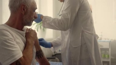 Doktor elleri kovid aşıyı enjekte ediyor yaşlı adam. Doktor kolu sterilize etti.