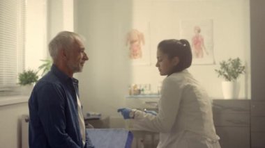 Serious doctor checking senior patient throat in hospital. Nurse examining man.