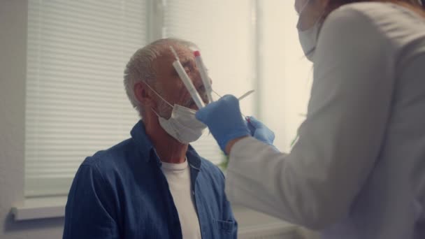 Nurse taking nasal swab covid test in elderly man closeup. Patient on checkup. — Vídeo de stock