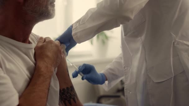 Mature patient getting vaccine dose in clinic closeup. Doctor vaccinating man. — Stockvideo