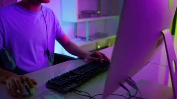 Closeup cyber man playing video game in headset. Neon computer equipment at home — Vídeos de Stock