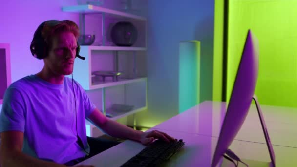 Cyber jugador hablando auriculares que se comunican con el equipo en la sala de neón de cerca. — Vídeos de Stock