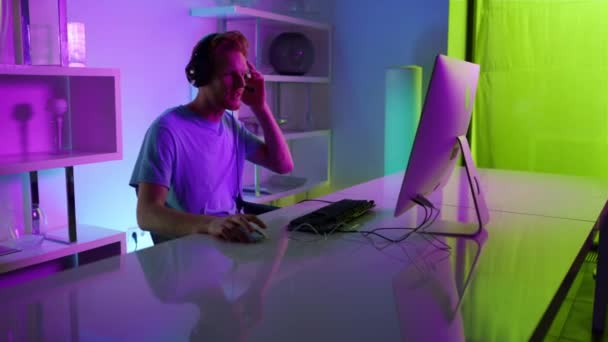 Excited gamer talking team on online stream in home neon cyberspace studio. — стоковое видео