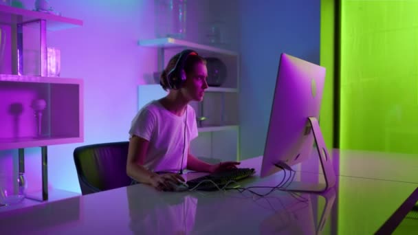 Heyecanlı kız siber uzay odasında oyun oynuyor. Kulaklıklı neon oyuncu — Stok video