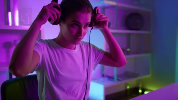 Closeup focused gamer putting headphones at home room. Cyberspace neon interior — Stock video