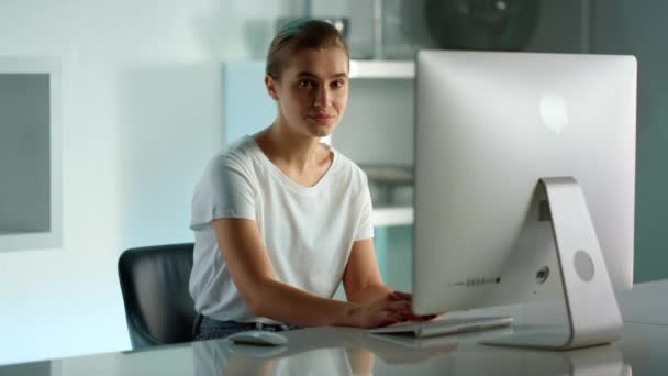Mujer sonriente usando computadora de escritorio en la oficina en casa. Vida de trabajador corporativo — Vídeos de Stock