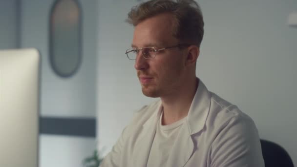 Portret van een knappe man arts in het kabinet. Artsen die met de computer werken. — Stockvideo