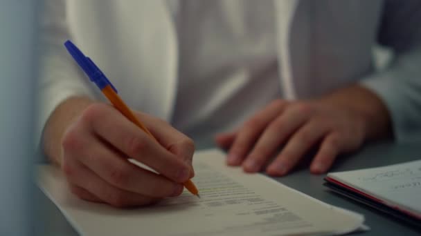 Man surgeon writing notes in medical journal sitting hospital office close up. — Stockvideo