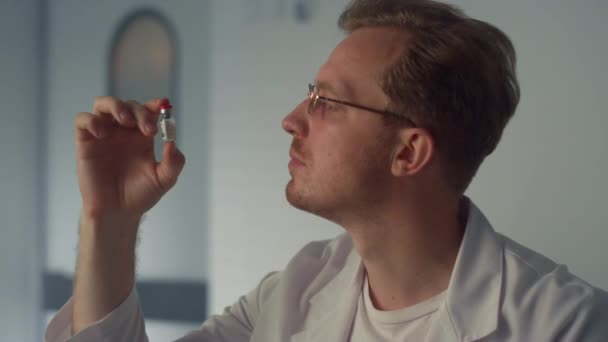 Doctor examining vaccine vial closeup. Physician considering vial with vaccine. — 비디오