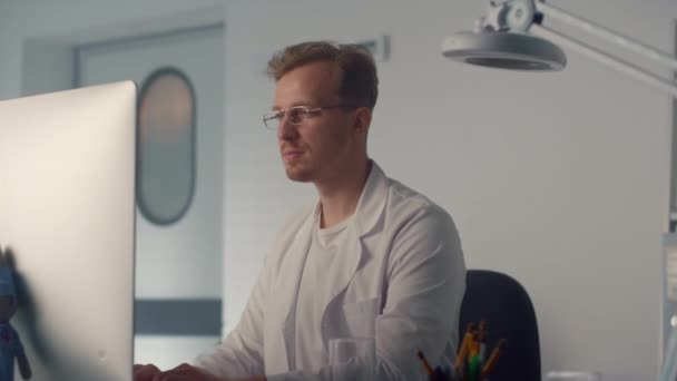 Portrétní doktor pracující s počítačem na moderní klinice. Sledování terapeuta. — Stock video
