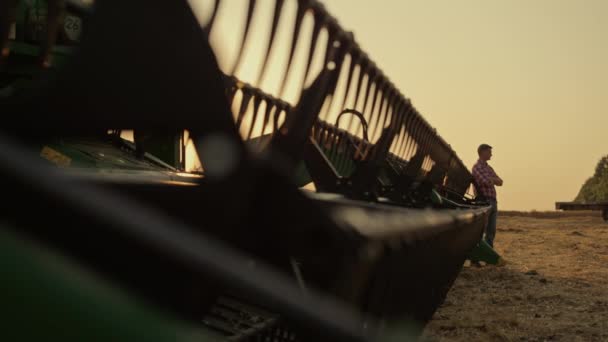 Agronomist silhouette rest wheat farmland lean harvester machine golden sunset. — 비디오