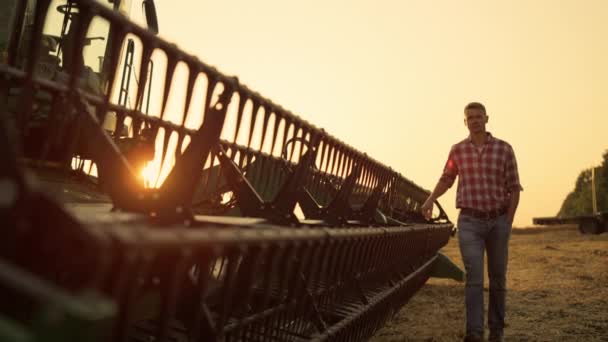 Munkás ellenőrzés össze cséplő vidék arany naplementekor. Gazdálkodó jármű — Stock videók