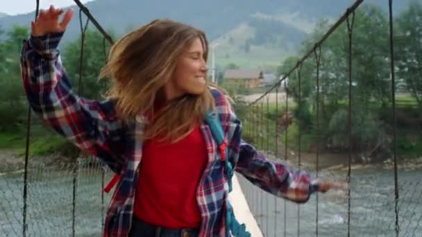 Reisender tanzt Bergwanderung auf Flussbrücke. Fröhliche Frau bewegt Körper nach draußen — Stockvideo
