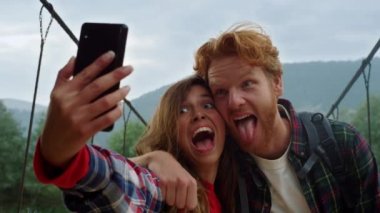 Mutlu çift cep telefonuyla fotoğraf çekiyor. Arkadaşlar dağlarda seyahat etmekten hoşlanır..