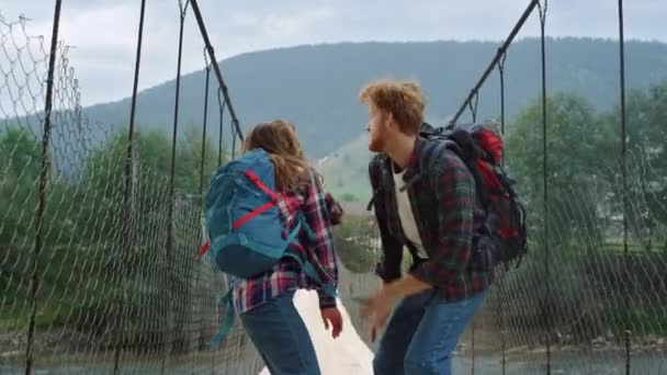 Dva stopaři si užívají skok na horském mostě. Šťastný pár tanec venku — Stock video