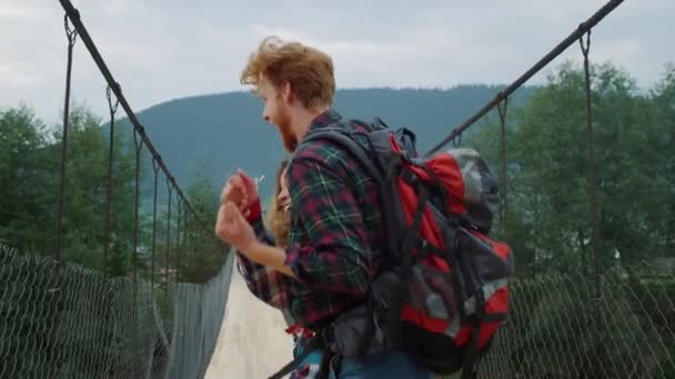 Viajantes alegres casal torcendo na ponte da montanha. Conceito de estilo de vida ativo — Vídeo de Stock