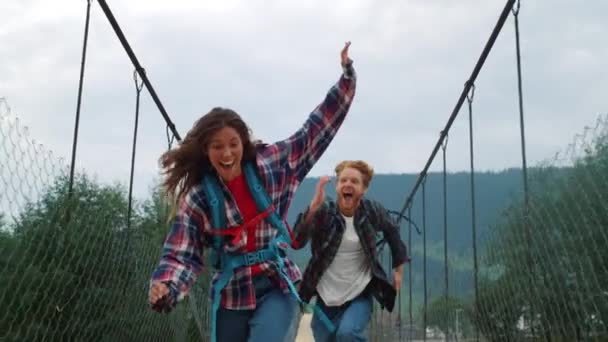 Due viaggiatori si divertono sul ponte di montagna. Eccitato coppia giocare insieme al di fuori — Video Stock
