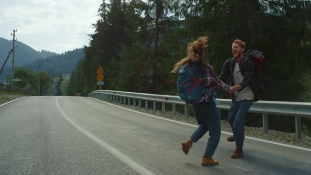 Amoureux dansant autour de la nature forestière sur la route des montagnes. Couple tenir la main à l'extérieur — Video