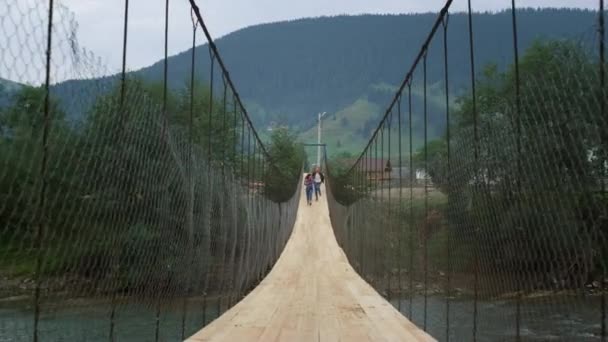 Touristes courant pont de rivière dans les montagnes. Randonneurs s'amuser ensemble sur la nature — Video