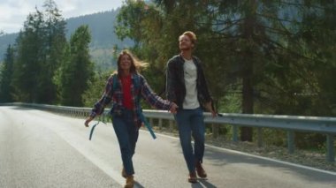 Mutlu aylaklar yaz dağlarında otostop çekmekten hoşlanırlar. Yürüyüşçüler yol kenarında yürüyor.