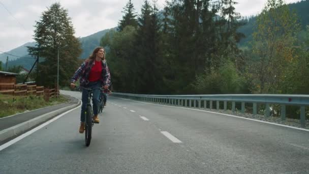 Les touristes aiment faire du vélo à l'extérieur sur la route forestière. Couple regardant autour des montagnes. — Video