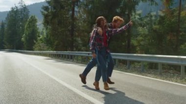 Hippiler dağlarda otostop çekerken eğleniyor. Otoyolda yürüyen turistler