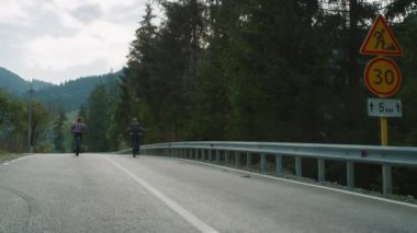 Otoyolda bisiklet süren sportif bir çift. Dağlarda bisiklet süren gezginler